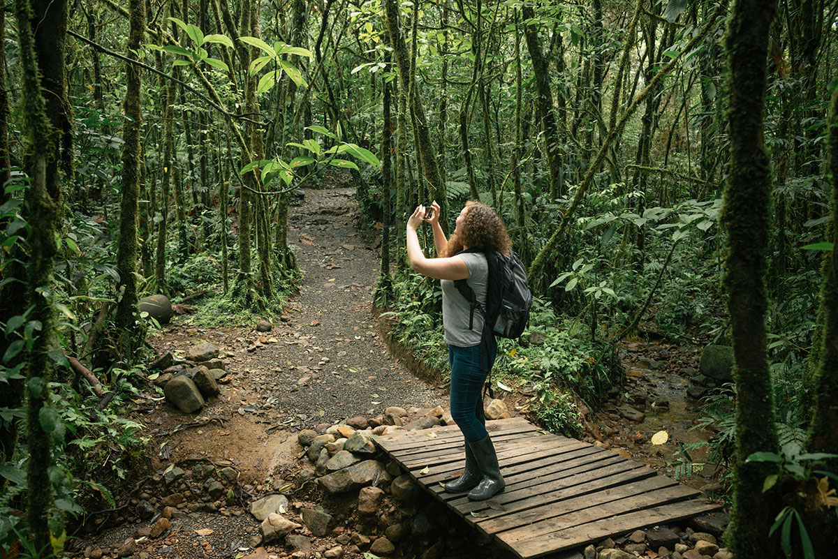 A woman stops to take a photo on her hike through the forests of Monteverde